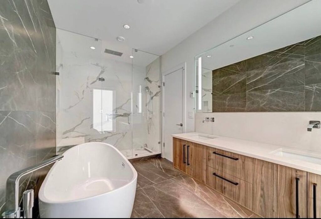 Primary bathroom with a freestanding tub, glass shower and double wood vanity
