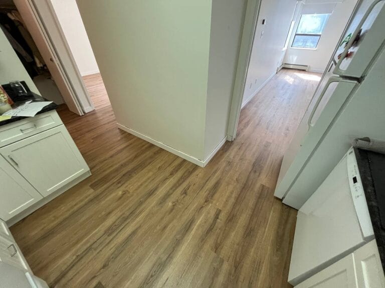 Kitchen entry with white cabinets and new warm plank flooring