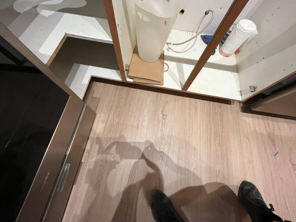 Light oak-look plank flooring installed under kitchen cabinet positions