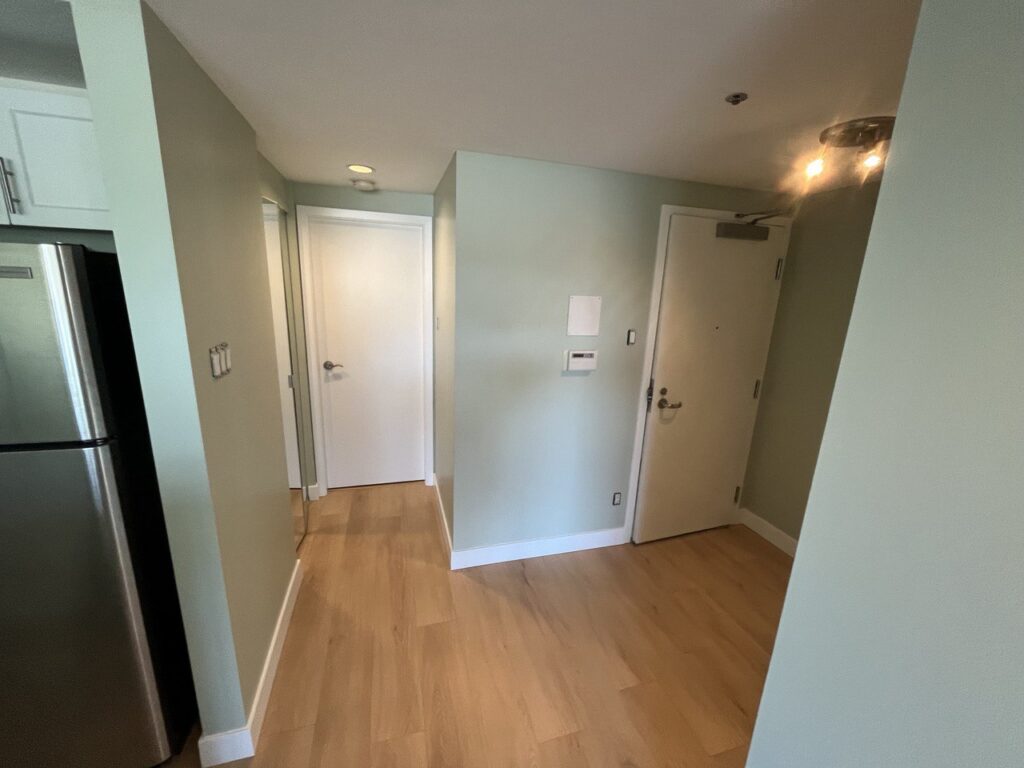 Warm oak-look flooring through a condo hallway and living area