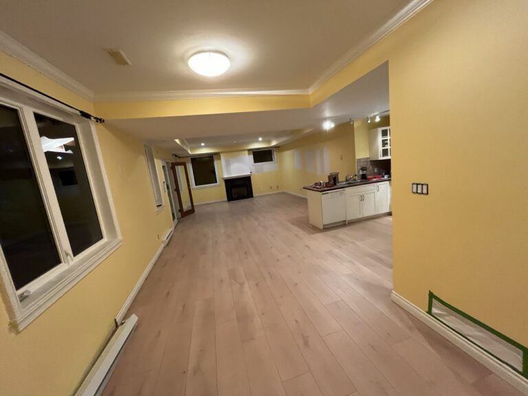 Open living area leading to a refreshed white kitchen with light oak flooring