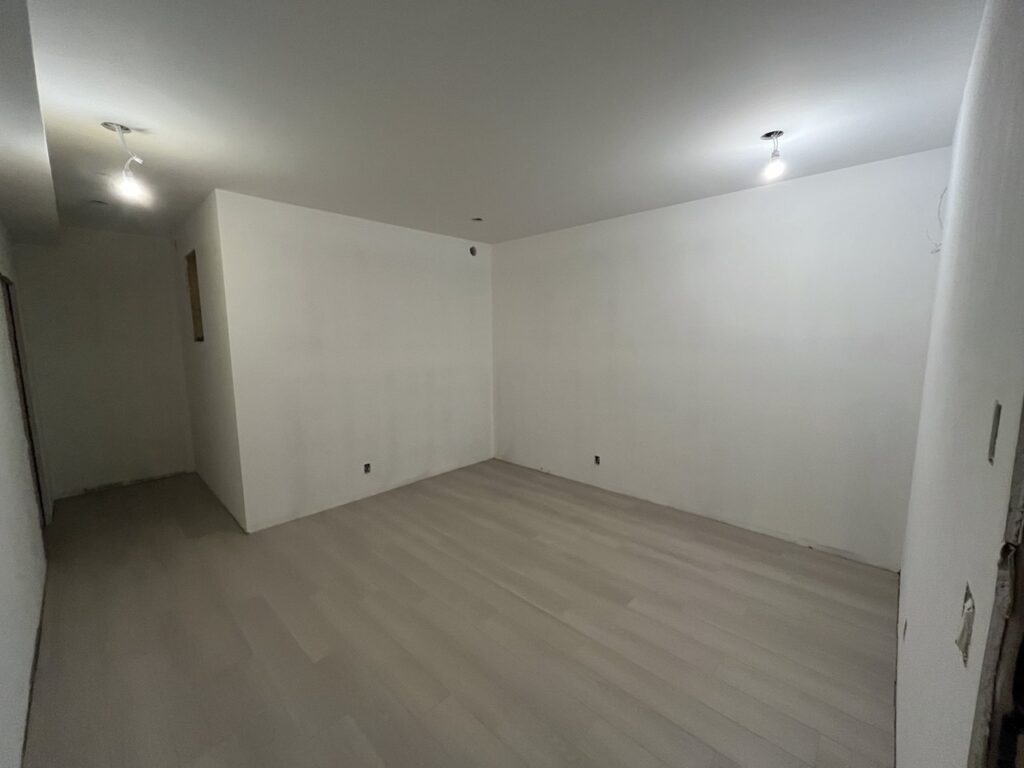 Finished room with new drywall and grey plank flooring