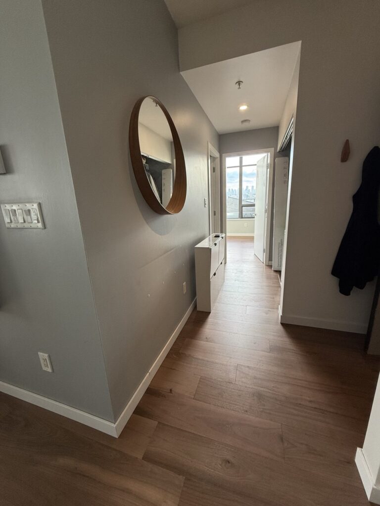 Hallway with new flooring, trim and round mirror after renovation