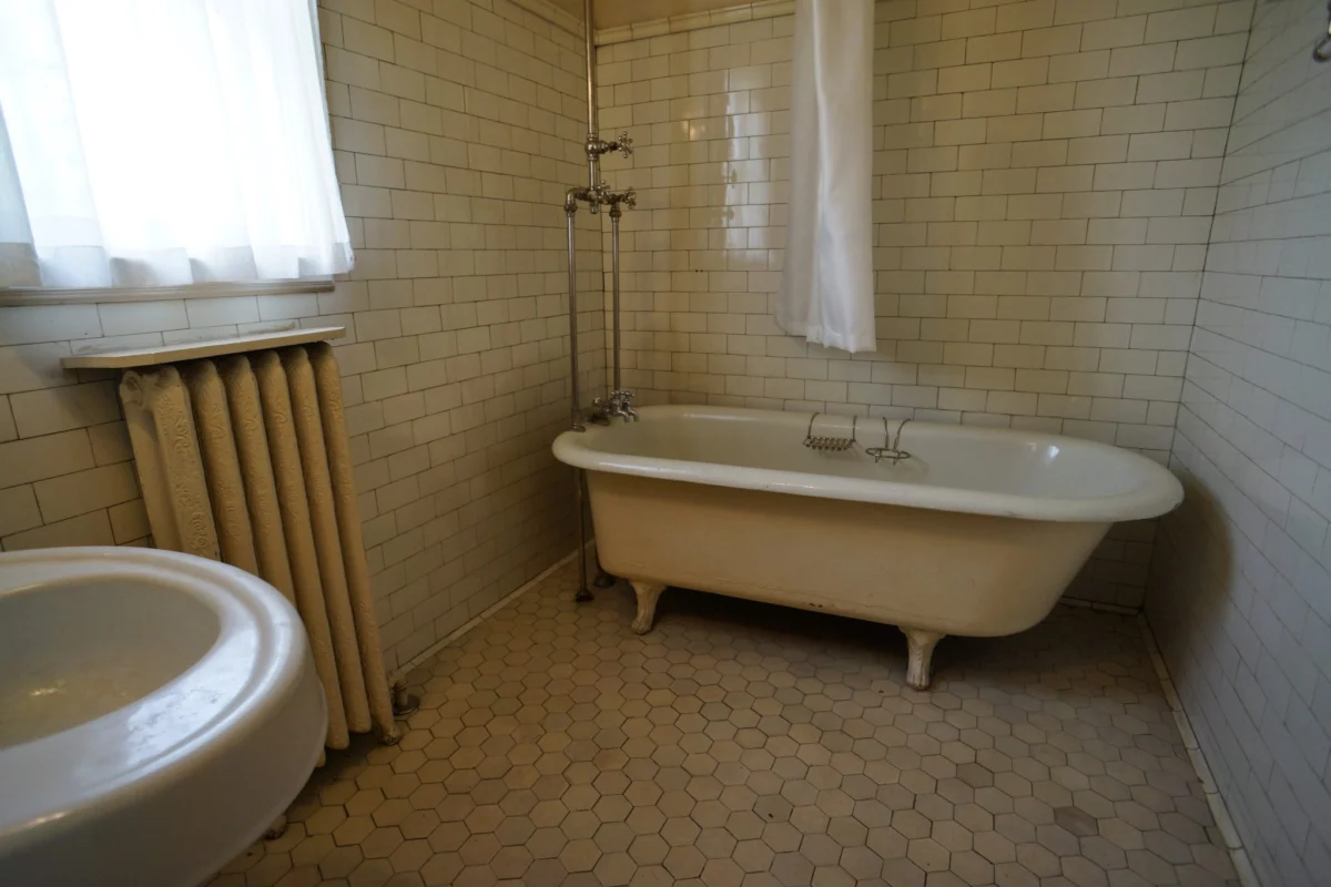 Bathtub in a tiled bathroom before conversion