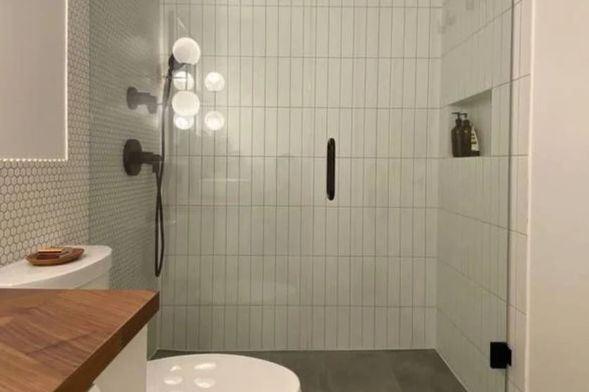 Finished bathroom with a walk-in glass shower, vertical white tile and a wood vanity top