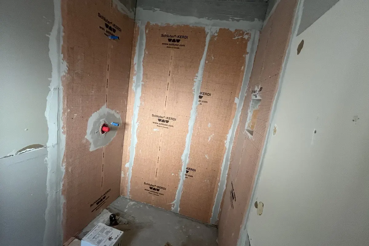 Shower walls covered in waterproofing membrane before tile during a bathroom renovation