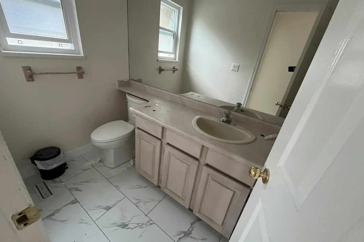 Bathroom with marble-look porcelain floor tile and a new toilet