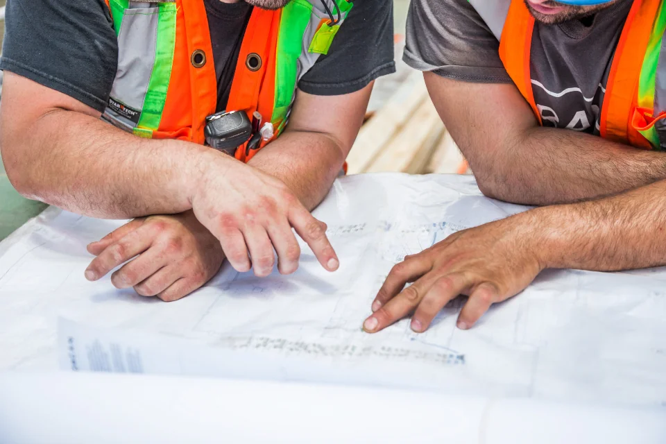 Two builders reviewing construction drawings on site
