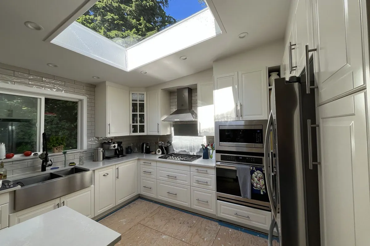 Renovated white kitchen with a skylight and stainless steel appliances